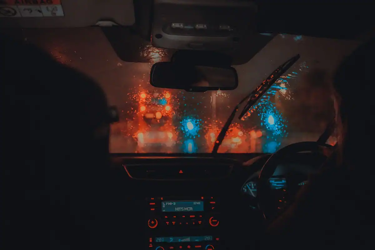 Parbriz ud pe timp de noapte, cu luminile traficului estompate de ploaia deasă