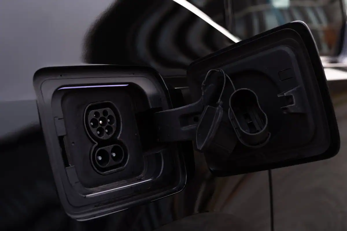 Portul de încărcare deschis al unei mașini electrice negre, văzut de aproape