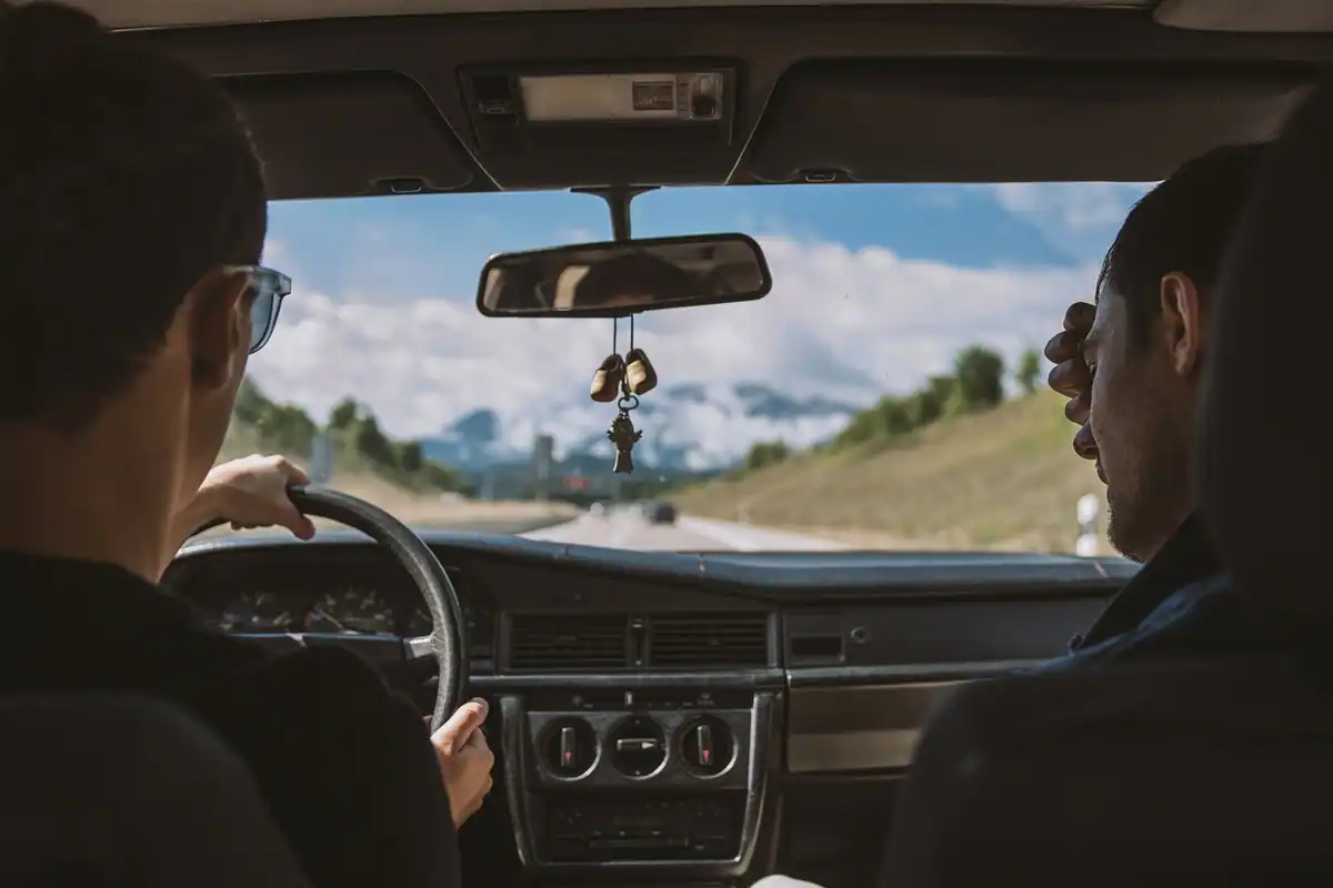 Oglinda retrovizoare a unei mașini în care se vede drumul din spate, esențială pentru un condus defensiv