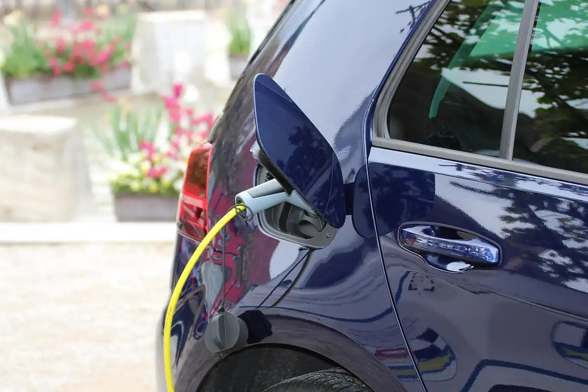 Ștecher de încărcare introdus într-o mașină electrică, văzut de aproape la o stație de încărcare