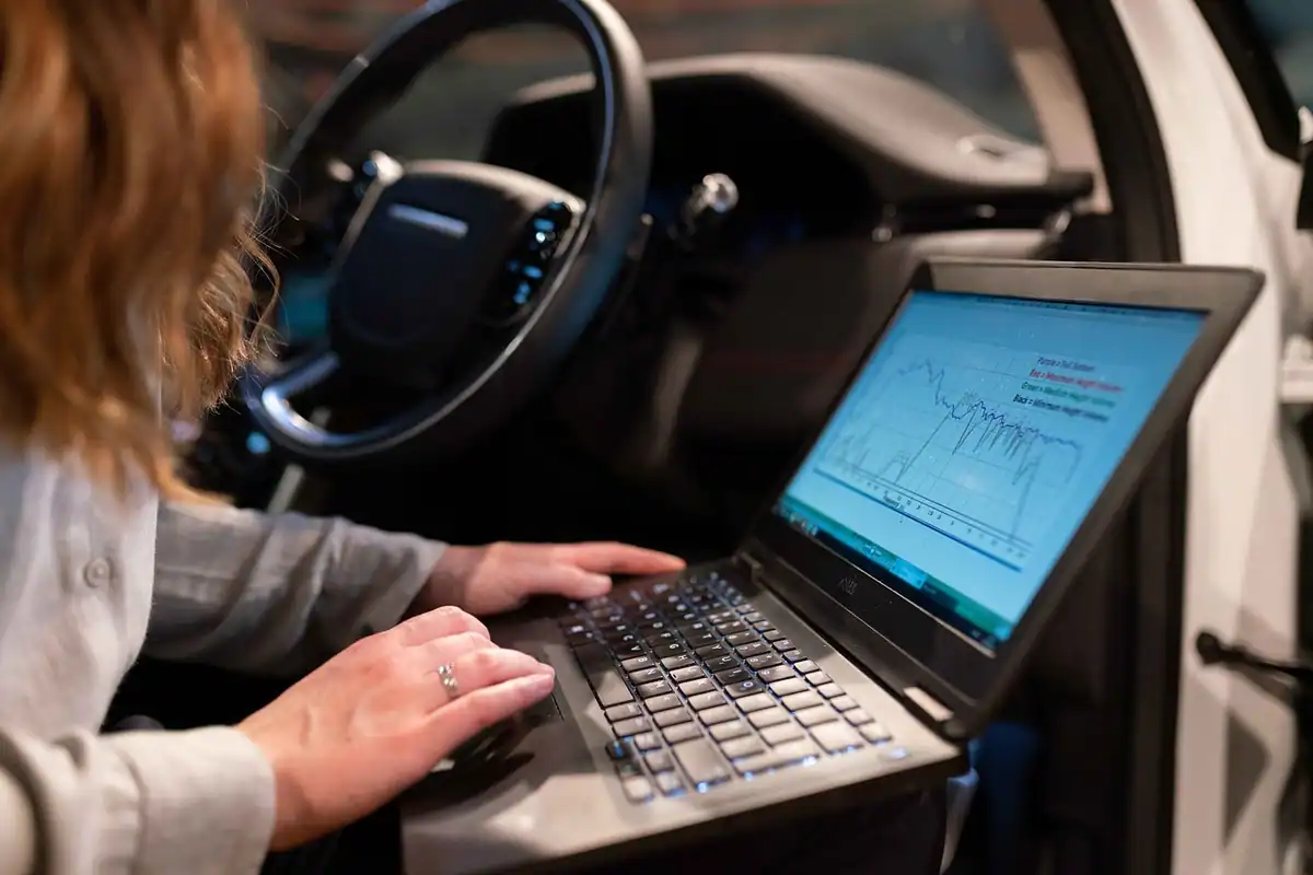 Femeie care lucrează la laptop în interiorul unei mașini electrice, pentru diagnoză