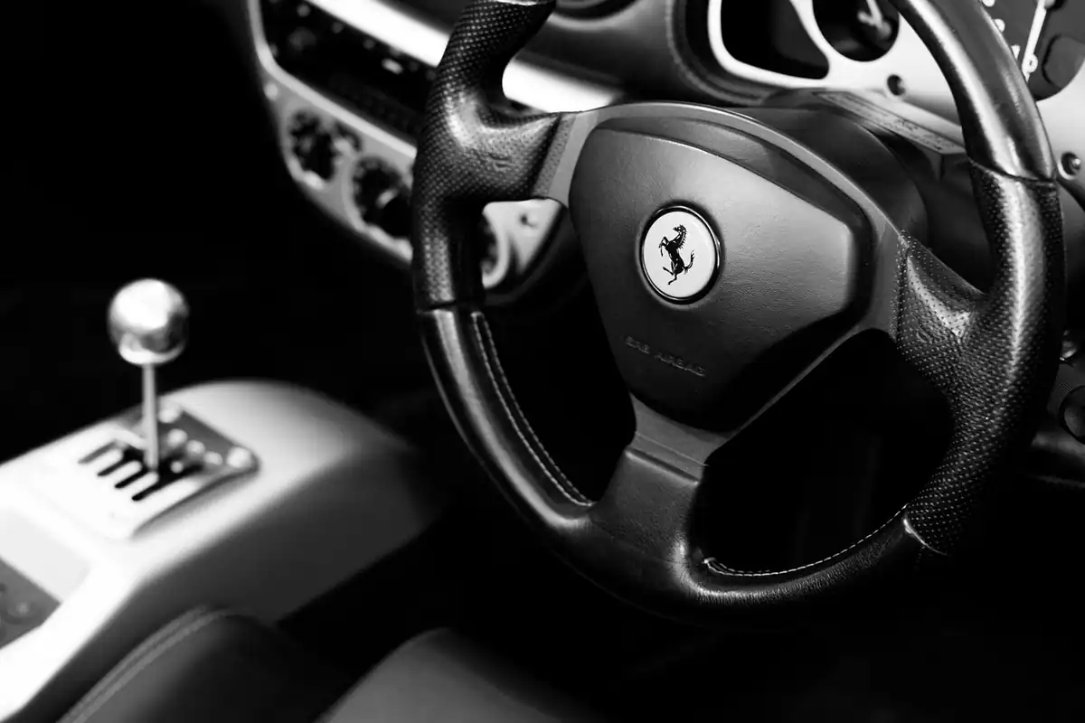 Bord și volan dintr-o mașină sport, cu aparate de bord unde se aprind martorii ESP și ai controlului tracțiunii