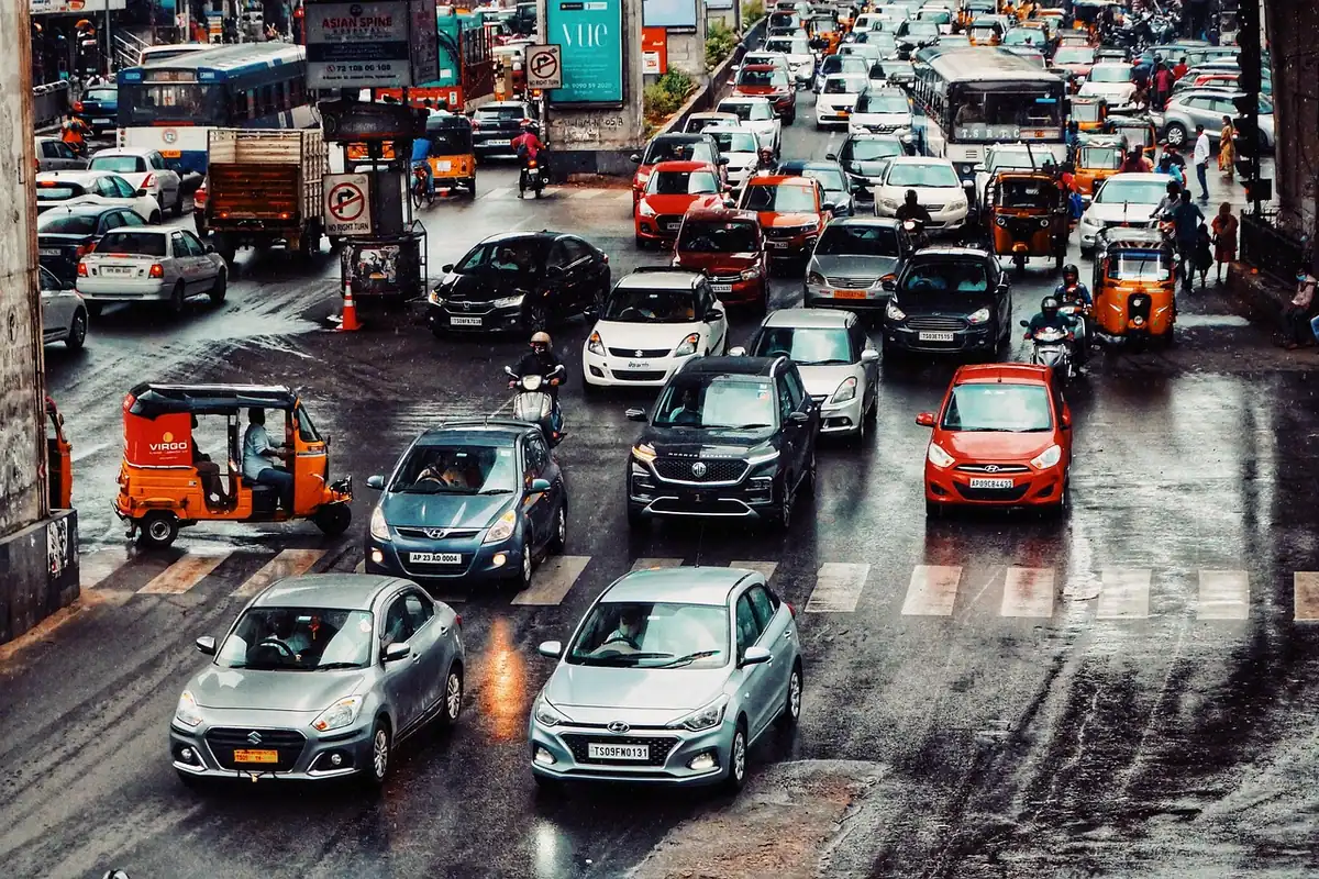 Trafic dens de oraș într-o intersecție, cu mașini la semafor, unde o mașină hibridă economisește combustibil