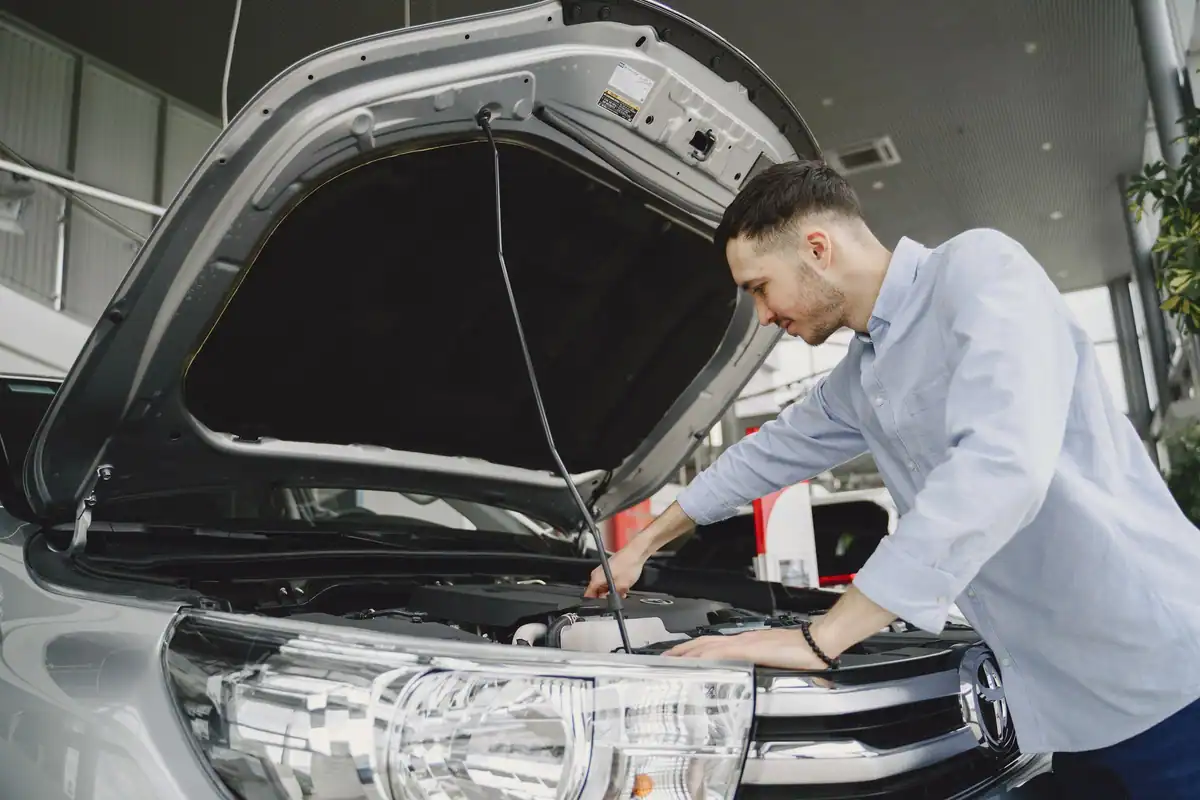 Bărbat care verifică motorul unei mașini cu capota ridicată în showroom
