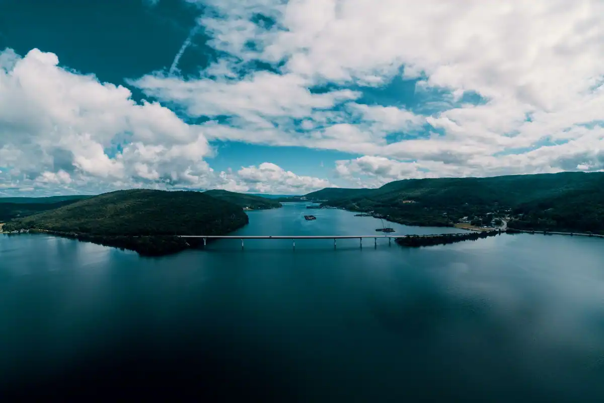 Pod lung peste un lac larg între dealuri, văzut de sus