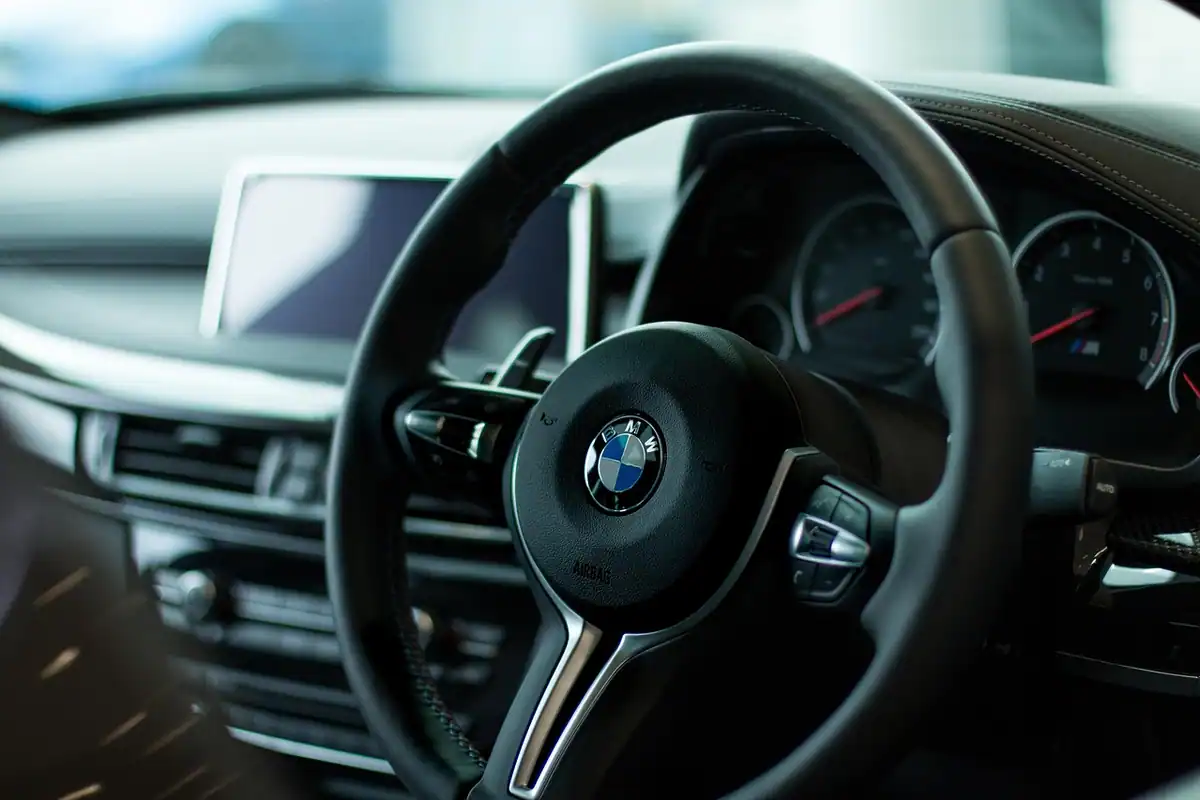 Permis de conducere ținut lângă volanul unei mașini BMW, document cu valabilitate și categorii