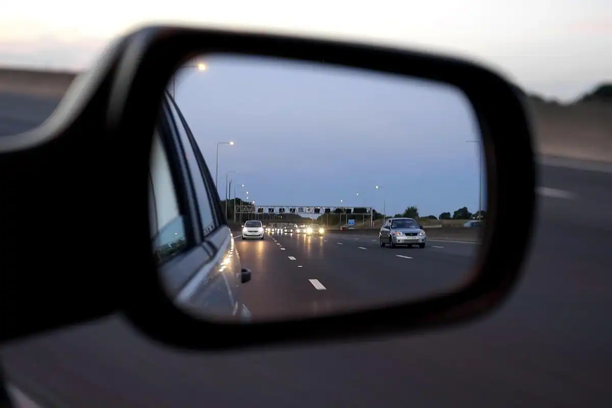 Oglindă laterală de mașină în care se reflectă drumul și trafic, reglată corect pentru a elimina unghiul mort